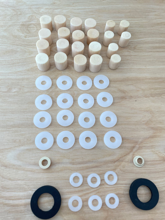 A complete set of elastomers, spacers, and end stops for a Votec GS4 suspension fork, suitable for a rider weight of 60 kg, neatly arranged on a wooden surface. The elastomers and washers are sorted by size and function.
